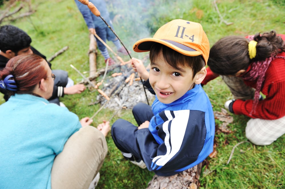 Barbecue in nature, group of children  preparing sausages on fire